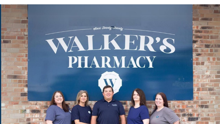 Walker Pharmacy team in front of the pharmacy sign